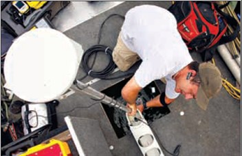 Jason McAlister of the Blackland Research Center sets up his global positioning satelite antenna on a pontoon boat at Granger lake last week. McAlister is mapping the sedimentation history of the lake floor.